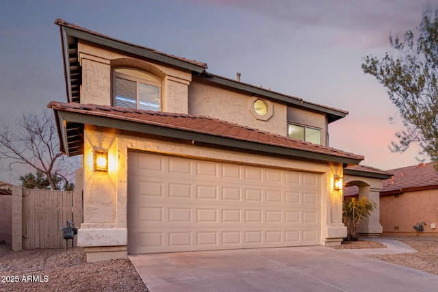 view of front of house featuring driveway, an attached garage, a tiled roof, and stucco siding