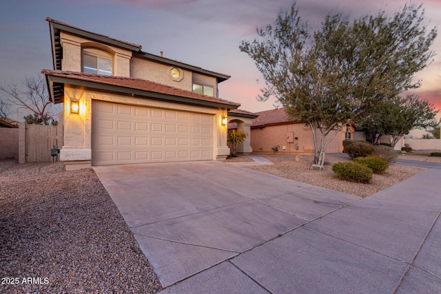 view of front of home with a garage, concrete driveway, fence, and stucco siding