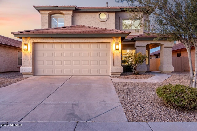 mediterranean / spanish home featuring a tiled roof, concrete driveway, and stucco siding