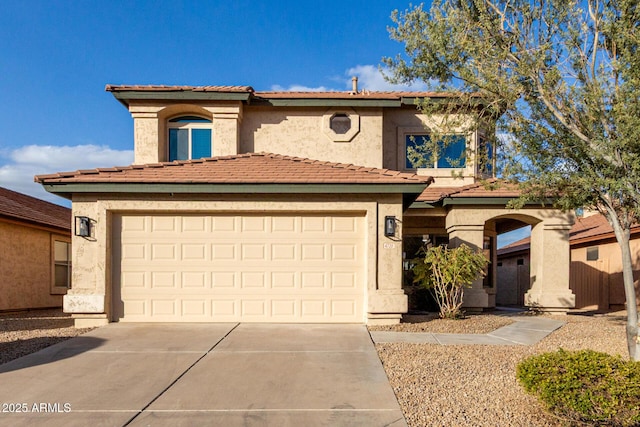 mediterranean / spanish-style home with a garage, a tiled roof, concrete driveway, and stucco siding