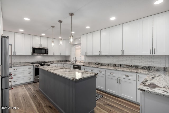 kitchen with stainless steel appliances, white cabinetry, a sink, and dark wood-style floors