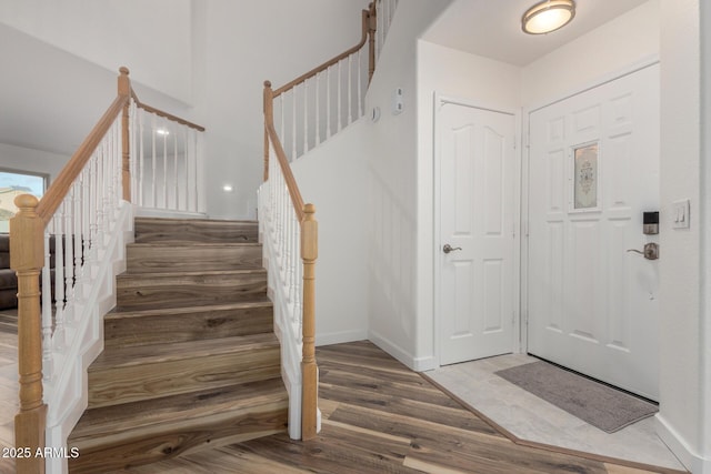 entrance foyer with stairs, wood finished floors, and baseboards