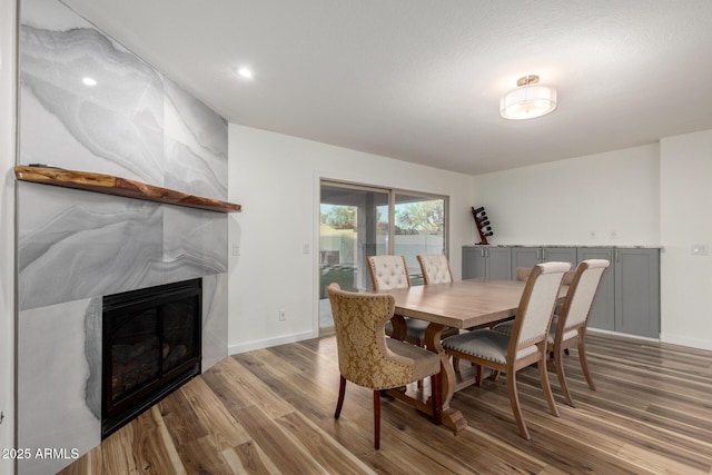 dining area with baseboards, wood finished floors, and a glass covered fireplace