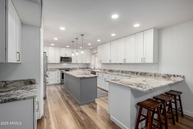 kitchen featuring a peninsula, light wood-style floors, white cabinetry, and appliances with stainless steel finishes