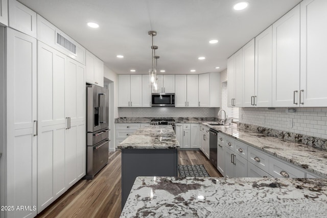 kitchen with stainless steel appliances, dark wood-type flooring, a sink, and decorative backsplash