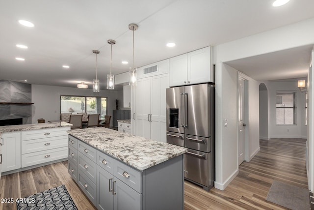 kitchen with arched walkways, recessed lighting, high end refrigerator, visible vents, and white cabinets