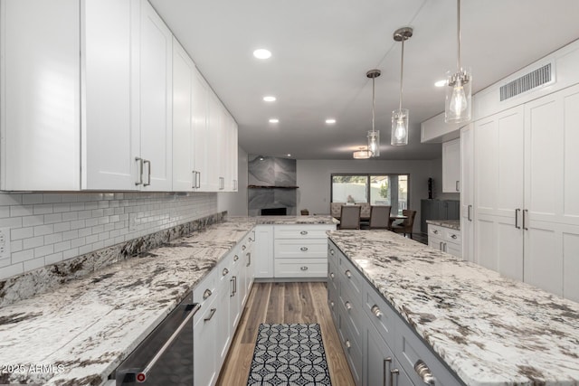 kitchen with light stone counters, visible vents, backsplash, dark wood-type flooring, and white cabinetry