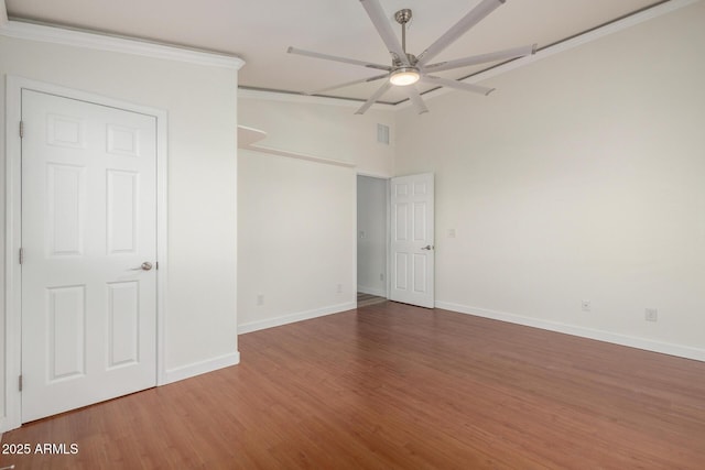 unfurnished room featuring baseboards, visible vents, a ceiling fan, and wood finished floors