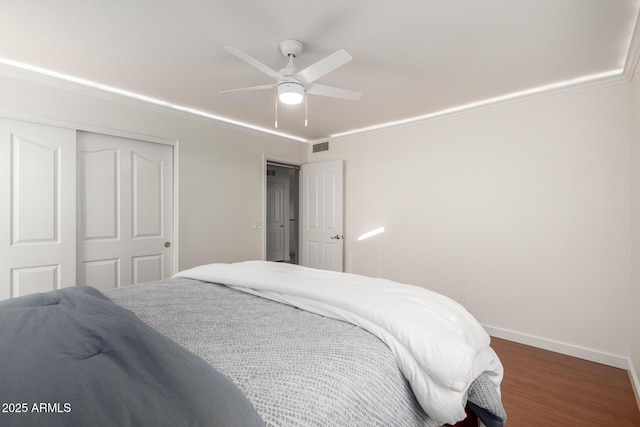 bedroom featuring a closet, ornamental molding, ceiling fan, wood finished floors, and baseboards