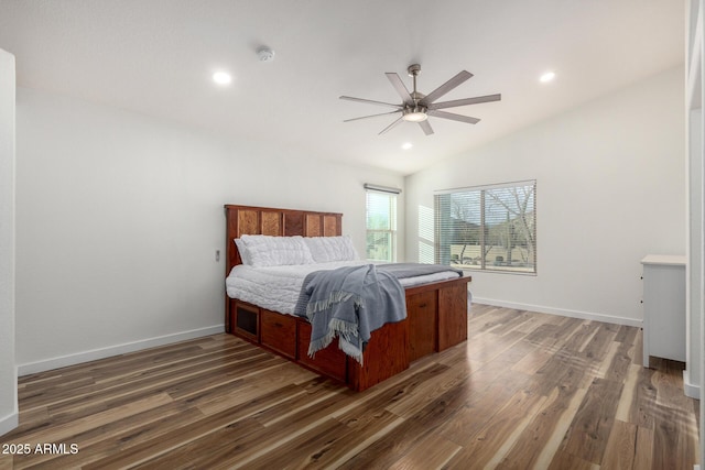 bedroom with vaulted ceiling, wood finished floors, and baseboards