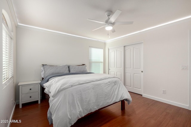 bedroom with baseboards, ceiling fan, ornamental molding, wood finished floors, and a closet