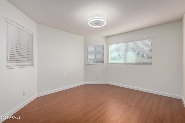 spare room featuring baseboards and wood finished floors