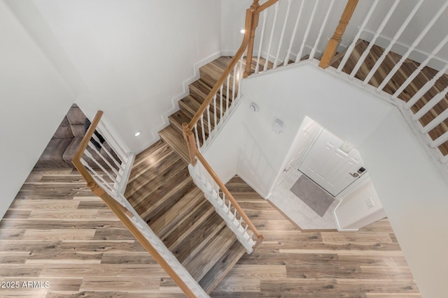 stairway with a towering ceiling and wood finished floors