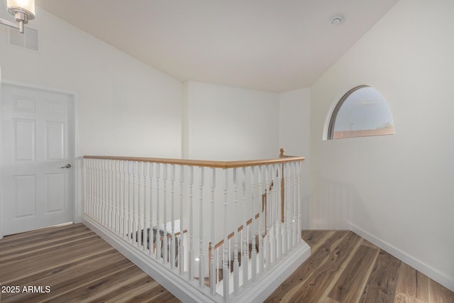 corridor featuring visible vents, wood finished floors, an upstairs landing, and baseboards