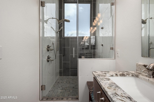 bathroom featuring a textured wall, a shower stall, and vanity