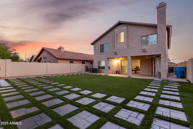 back of property with central air condition unit, stucco siding, a lawn, a patio area, and a fenced backyard