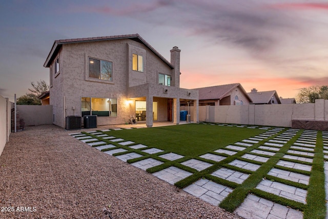 rear view of house with a lawn, a fenced backyard, cooling unit, a patio area, and stucco siding