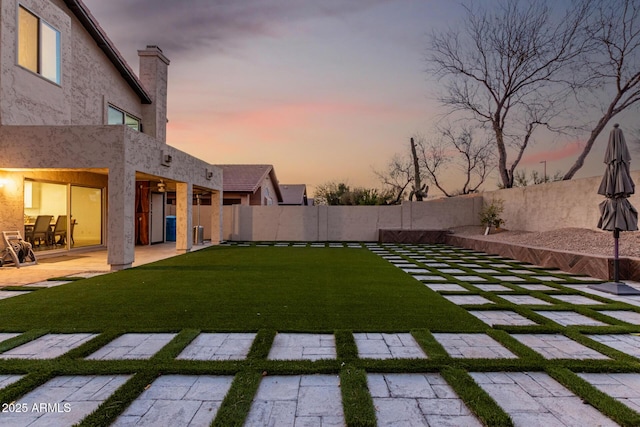 yard at dusk with fence and a patio