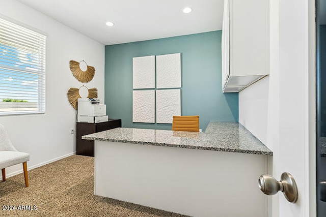 kitchen with light stone counters, light carpet, and white cabinets