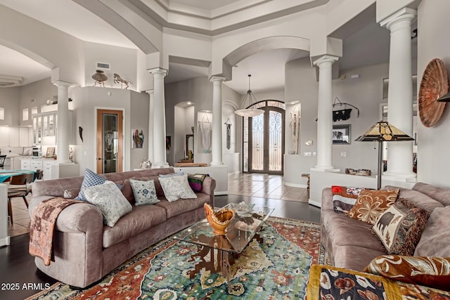 tiled living room featuring ornate columns and a towering ceiling