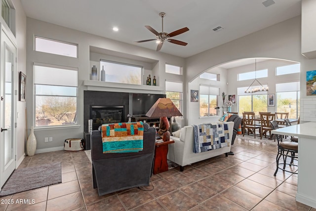 tiled living room with ceiling fan with notable chandelier