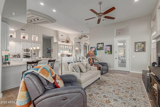 tiled living room featuring ceiling fan and a high ceiling