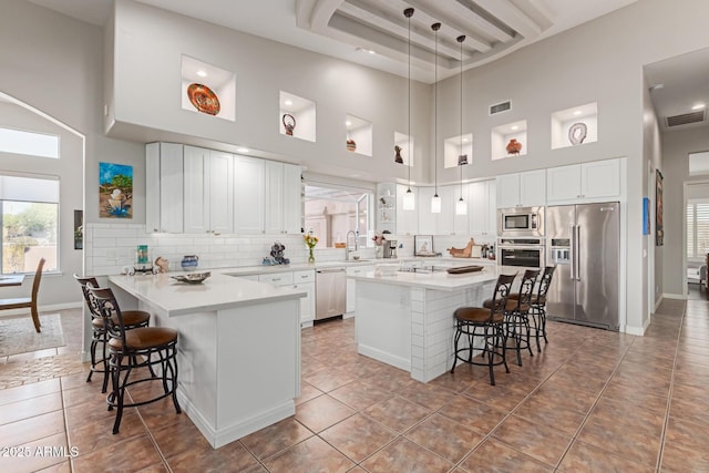 kitchen featuring pendant lighting, white cabinetry, stainless steel appliances, and a kitchen bar