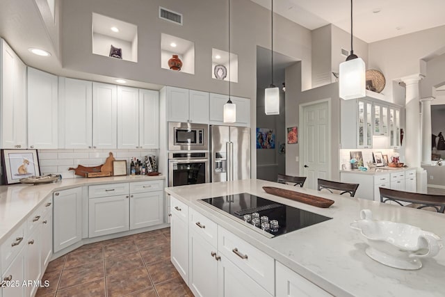 kitchen with light stone counters, pendant lighting, white cabinets, and appliances with stainless steel finishes