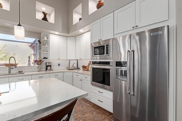 kitchen with white cabinetry, sink, decorative light fixtures, and stainless steel appliances