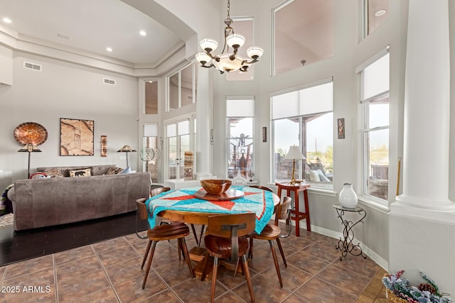 tiled dining space with an inviting chandelier, a wealth of natural light, decorative columns, and a high ceiling