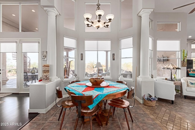 dining area with a towering ceiling, dark tile patterned flooring, decorative columns, and a notable chandelier