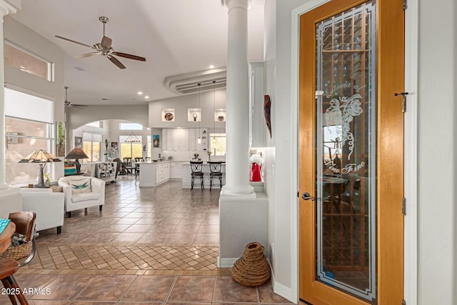 tiled entryway with decorative columns, vaulted ceiling, and ceiling fan