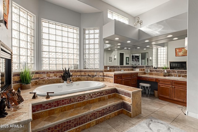 bathroom with tile patterned flooring, vanity, and tiled bath