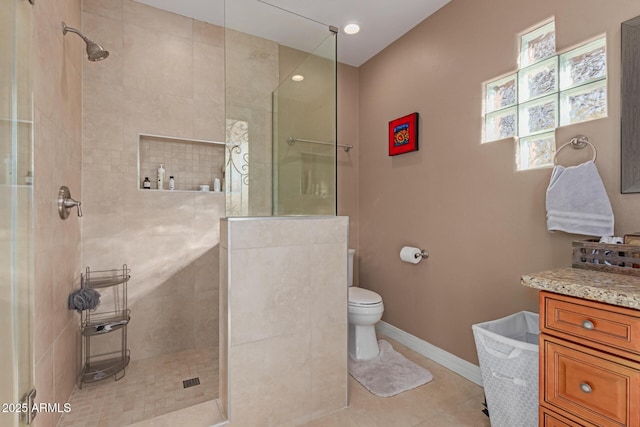 bathroom featuring vanity, toilet, tile patterned flooring, and a tile shower