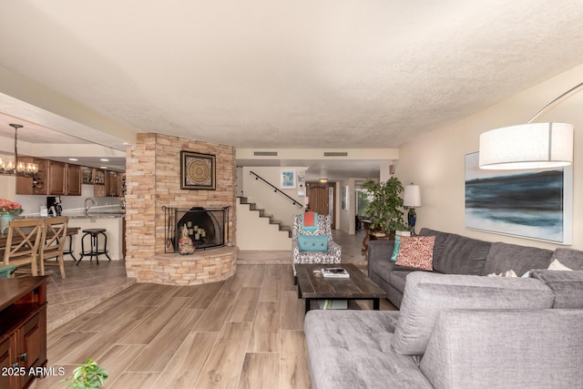 living room featuring a fireplace, a chandelier, a textured ceiling, and sink