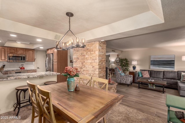 dining room featuring a tray ceiling, light hardwood / wood-style flooring, and a notable chandelier