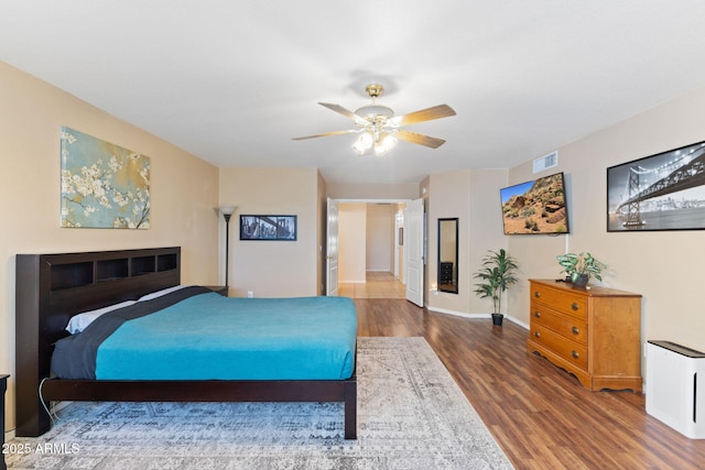 bedroom featuring a ceiling fan, visible vents, baseboards, and wood finished floors