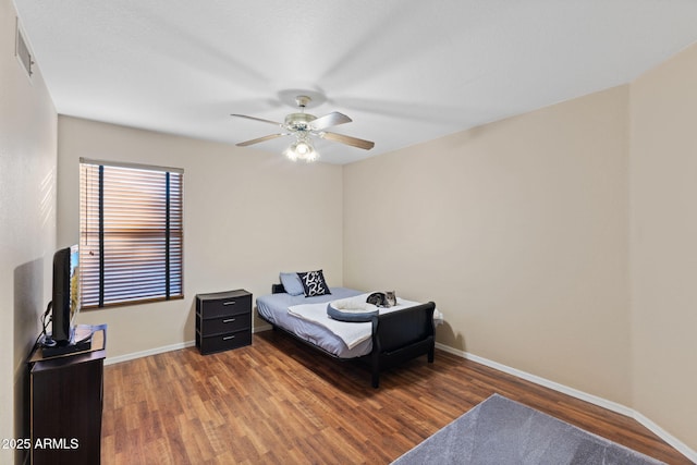 bedroom featuring a ceiling fan, visible vents, baseboards, and wood finished floors