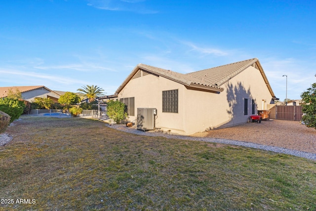 view of property exterior with a lawn, a tiled roof, a gate, fence, and stucco siding