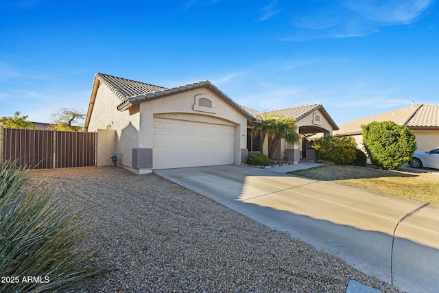 view of front facade featuring concrete driveway, a tiled roof, an attached garage, a gate, and stucco siding