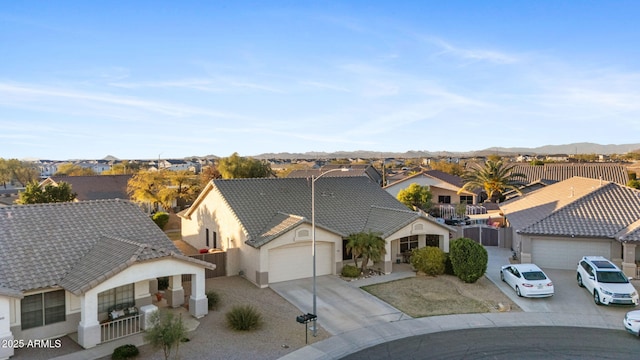 view of front of property featuring an attached garage, driveway, a tile roof, and a residential view