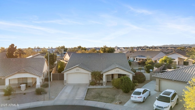 view of front of home with concrete driveway, a residential view, a tiled roof, an attached garage, and fence