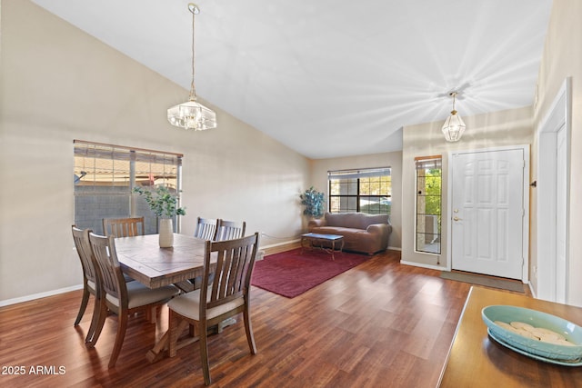 dining space featuring a notable chandelier, baseboards, vaulted ceiling, and wood finished floors