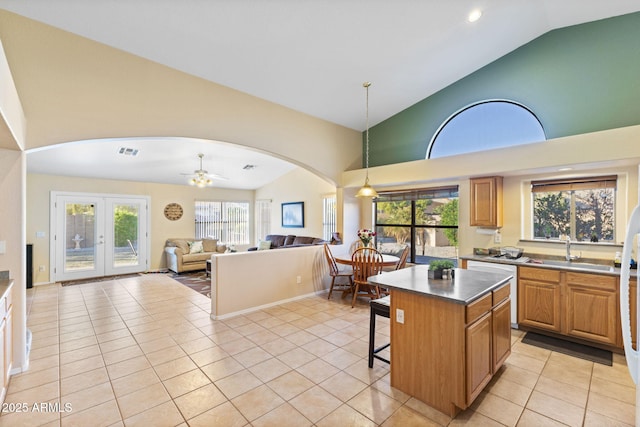 kitchen featuring light tile patterned floors, visible vents, arched walkways, a kitchen breakfast bar, and a sink