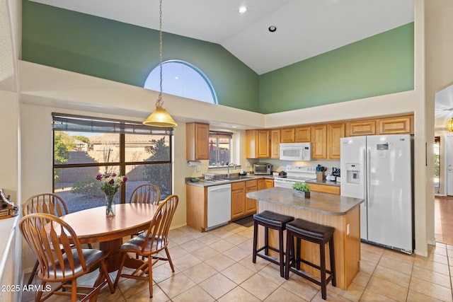 kitchen with white appliances, a kitchen island, light tile patterned floors, and a sink