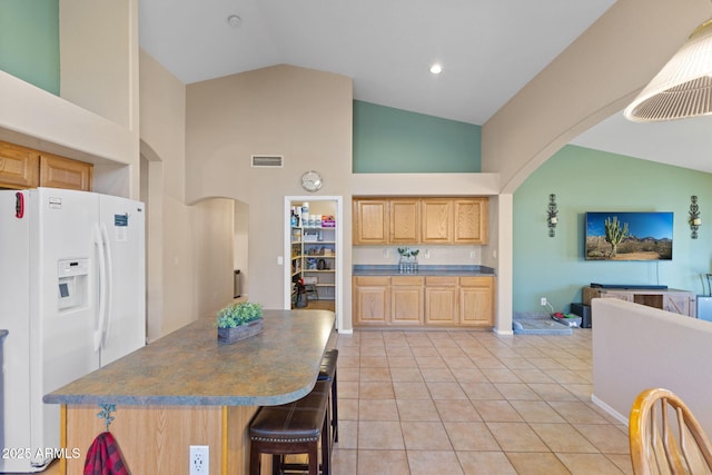 kitchen with arched walkways, white refrigerator with ice dispenser, light brown cabinets, and visible vents