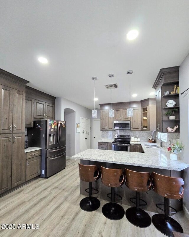 kitchen featuring sink, hanging light fixtures, kitchen peninsula, a breakfast bar, and appliances with stainless steel finishes