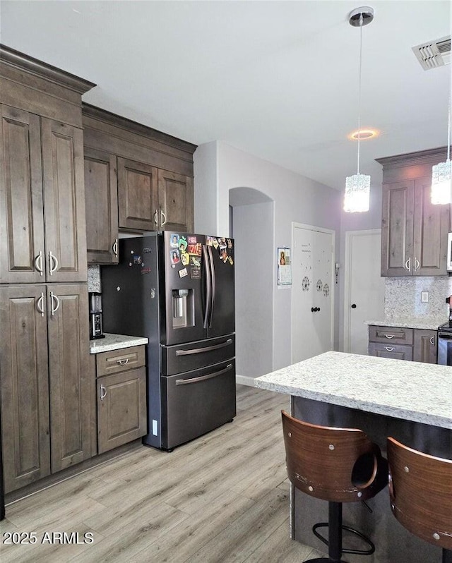 kitchen with dark brown cabinets, decorative light fixtures, decorative backsplash, and stainless steel fridge with ice dispenser