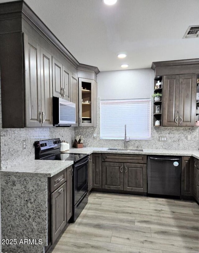 kitchen with black appliances, sink, light wood-type flooring, dark brown cabinets, and light stone counters