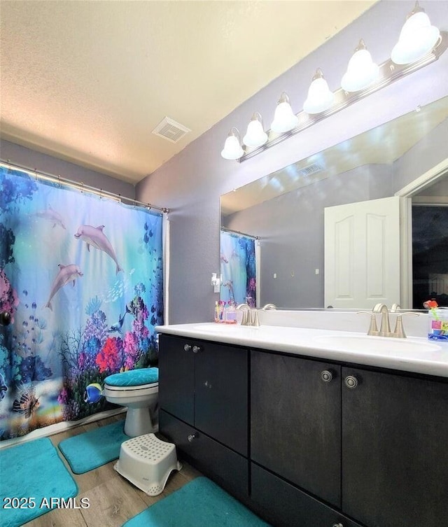 bathroom with walk in shower, vanity, wood-type flooring, and toilet